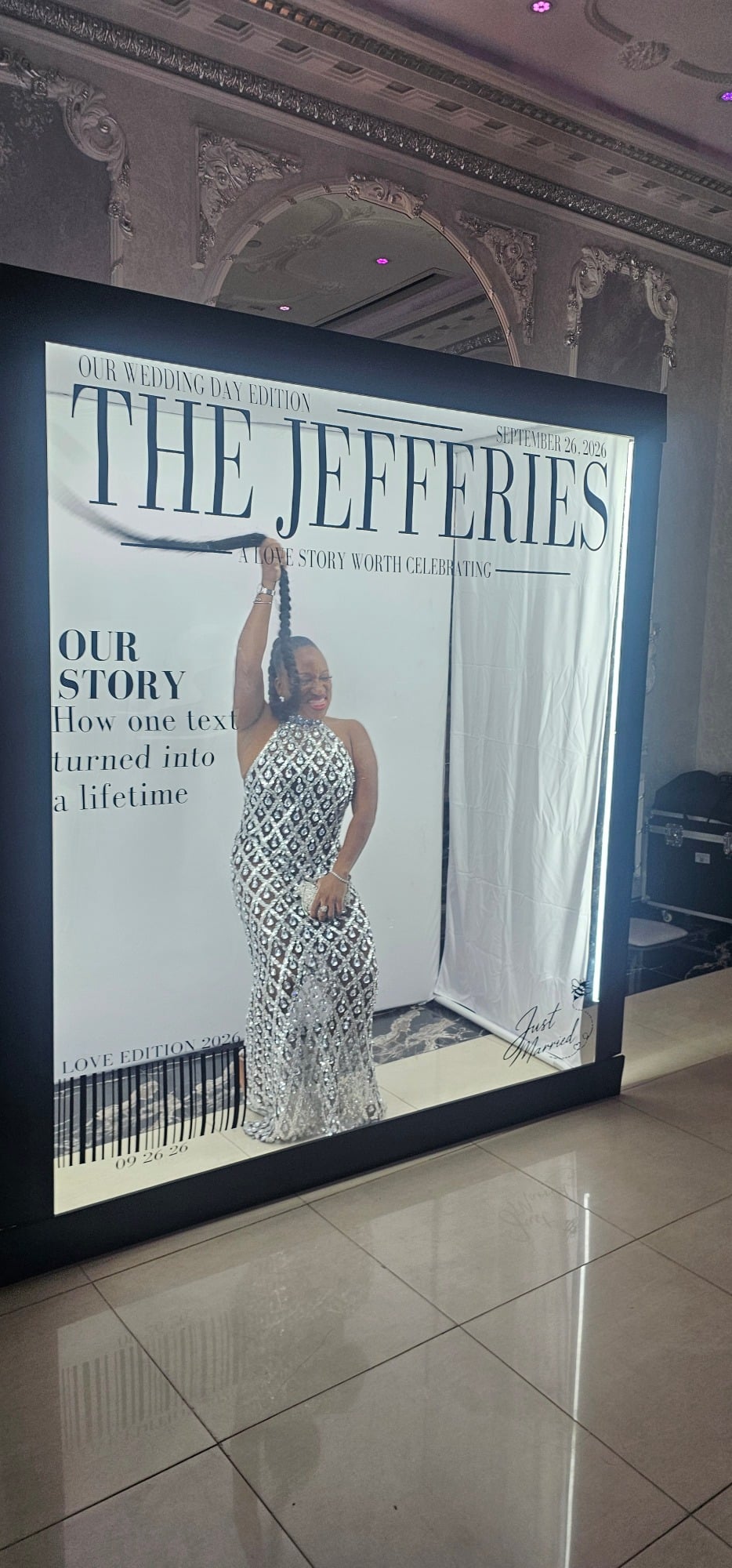 Woman in patterned dress posing with braided hair inside a large magazine cover prop frame.