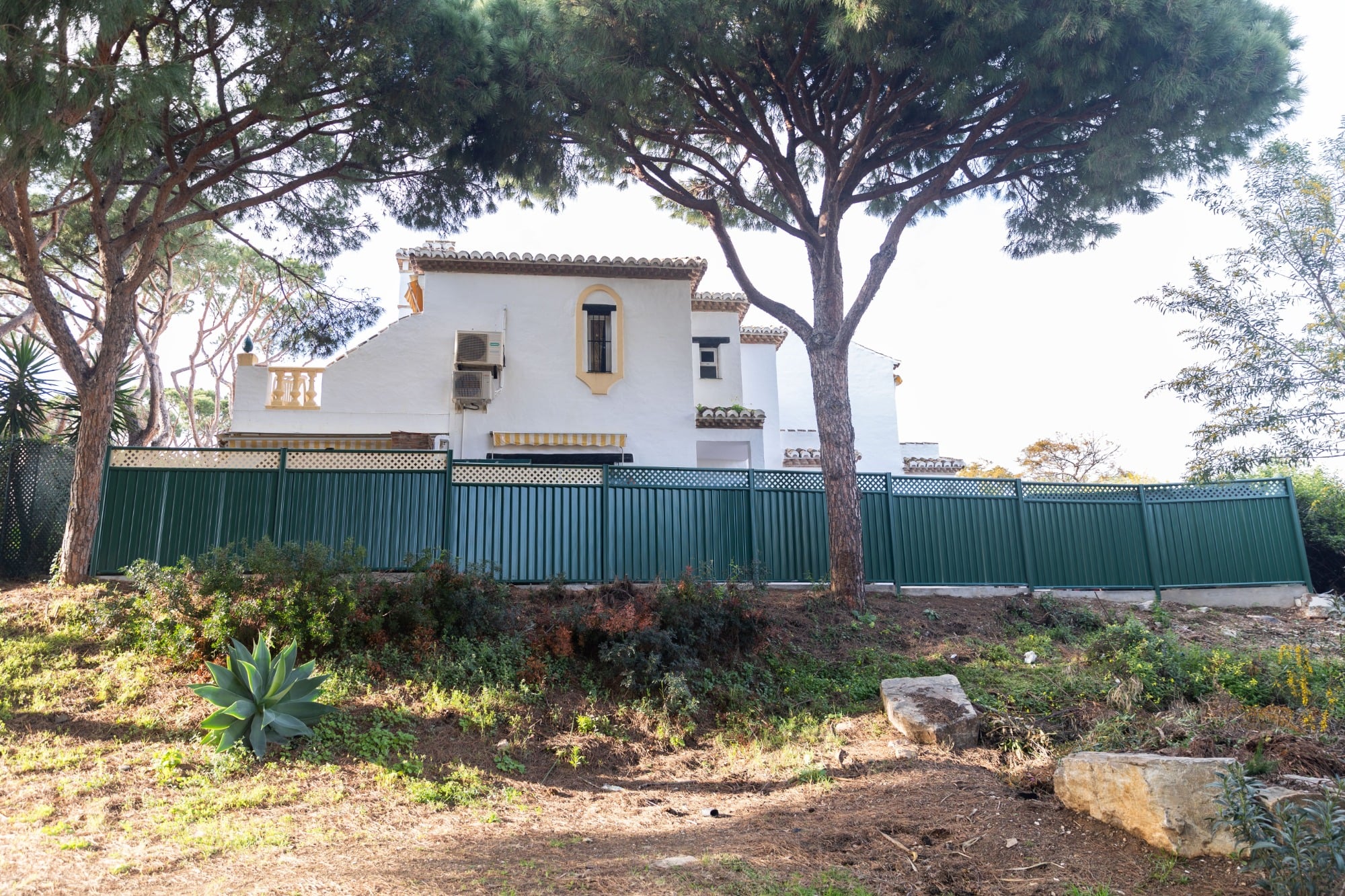 Green ColourFence steel garden fence with vertical panels and matching posts beside a white residential building.